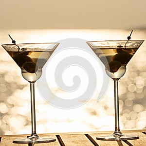 Two martini cocktails at the wooden pier at sunset. Luxury resort vacation concept. Festive relax getaway background.