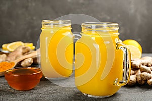 Two mason jars of immunity boosting drink and ingredients on grey table, closeup