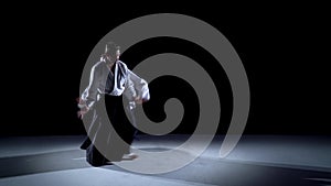 Two masters participants of the training in special clothes of Aikido Hakama work out the methods of single combat on