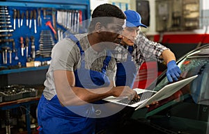 Two masters are replacing the filter in car on workplace