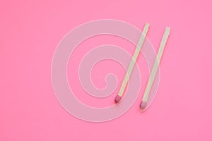 Two matches on a pink paper table