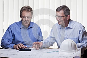 Two mature architects or engineers calcutating a project