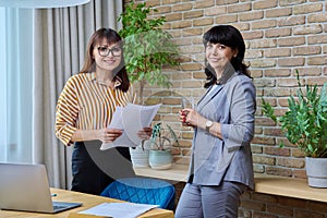 Two mature business women colleagues working together in office