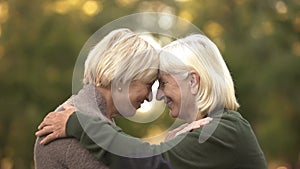 Two mature female friends tightly hugging each other and smiling, happy meeting