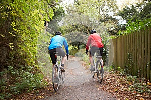 Two Mature Male Cyclists Riding Bikes Along Path