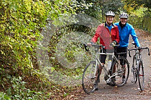 Two Mature Male Cyclists Riding Bikes Along Path