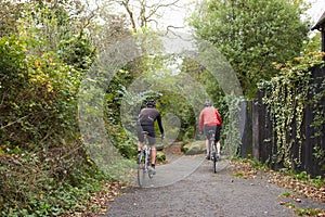 Two Mature Male Cyclists Riding Bikes Along Path