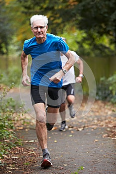 Two Mature Male Joggers Running Along Path photo