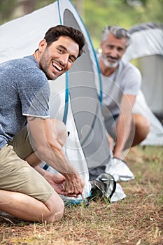 Two mature men erecting tent