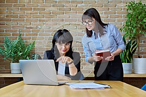 Two mature successful business women working together in office