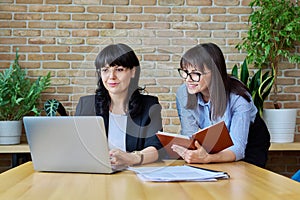 Two mature successful business women working together in office