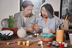 Two mature woman sitting at the table in pottery master class