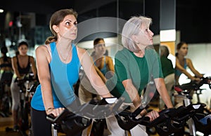 Two mature woman training on fitness bikes