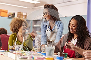 Two Mature Women Attending Art Class In Community Centre With Teacher