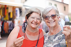 Two mature women with happy expression, take off the surgical maskes posing for family portrait. People, emotions and friendship