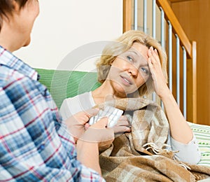 Two mature women with pill on couch