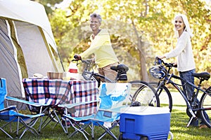 Two Mature Women Riding Bikes On Camping Holiday