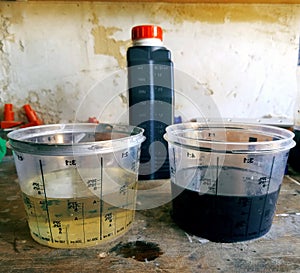 Two measuring glasses with clean and used engine oil