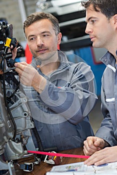 two mechanics fixing cars engine in garage