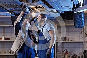 Two Mechanics Inspecting Car on Lift