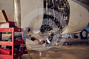 Two mechanics is working with civil airplane