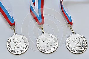 Two medals for 1st and 2nd place on a white-blue-red ribbon on a gray background