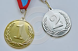 two medals for 1st and 2nd place on a white-blue-red ribbon on a gray background