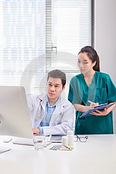 Two medical doctors consulting, smiling at office desk