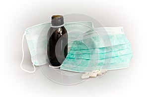 Two medical masks, pills and cough syrup bottle