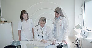 Two medical nurses and a specialist doctor review the results of medical examinations for their patients.