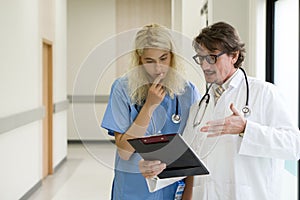 Two medical professionals engaging in a discussion within sanitized hospital corridors