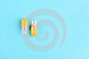 Two medicine capsules on blue background with copy space flat lay