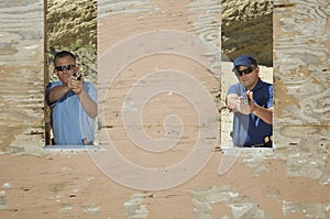 Two Men Aiming Hand Guns At Firing Range