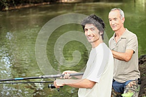 Two men angling beside river