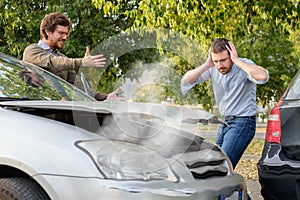 Two men arguing after a car accident on the road