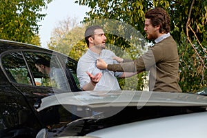 Two men arguing after a car accident on the road