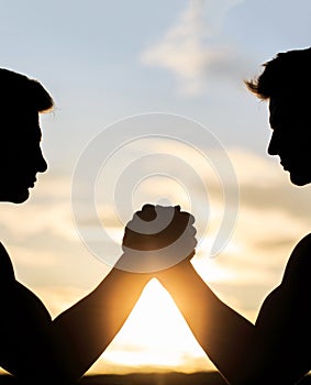 Two men arm wrestling. Rivalry, vs, challenge, strength comparison. Sunset, sunrise. Silhouette of hands that compete in