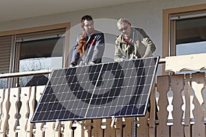 Two men assemble a balcony power plant to generate electricity