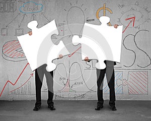 Two men assembling puzzles with business doodles background