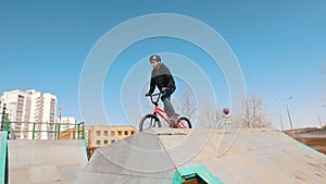 Two men on a bicycle going down hill in the skatepark