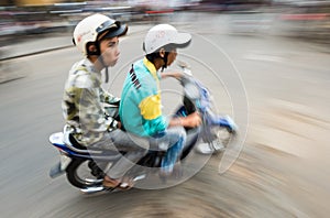 Two men on bike in Hoi An. View in motion.