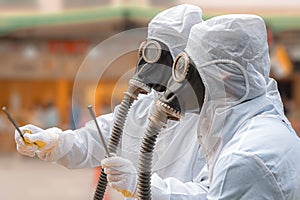 Two men in bio-hazard suit and gas mask.