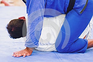 Two unidentifiable men practicing Brazilian Jiu-Jitsu on a blue mat photo
