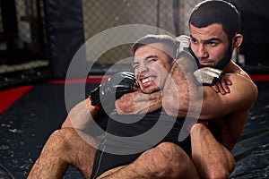 Two men boxers in gloves are fighting at gym using grappling