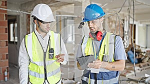 Two men builders using touchpad at construction site