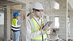 Two men builders using touchpad at construction site