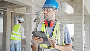 Two men builders using touchpad at construction site