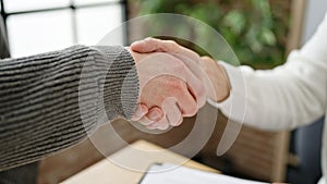 Two men business partners shake hands at office