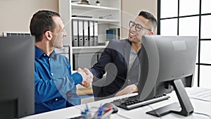 Two men business workers using computer shake hands at office