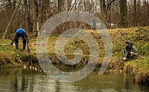 Two men catch fish netting in a pond in a village